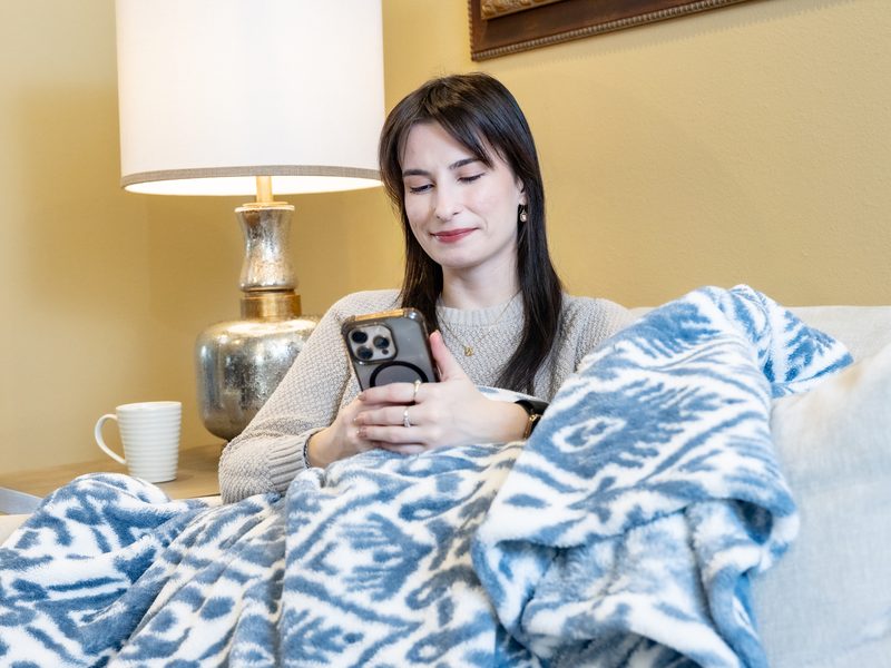 Woman relaxing under a blanket in a warm home